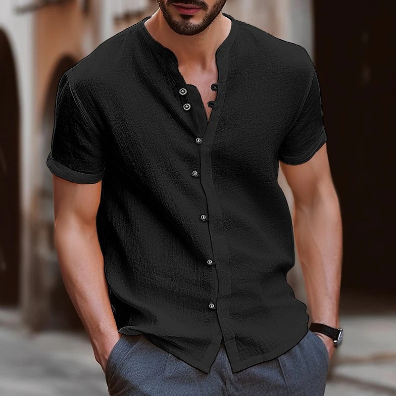 Man wearing a black short-sleeve button-up shirt with a blurred background