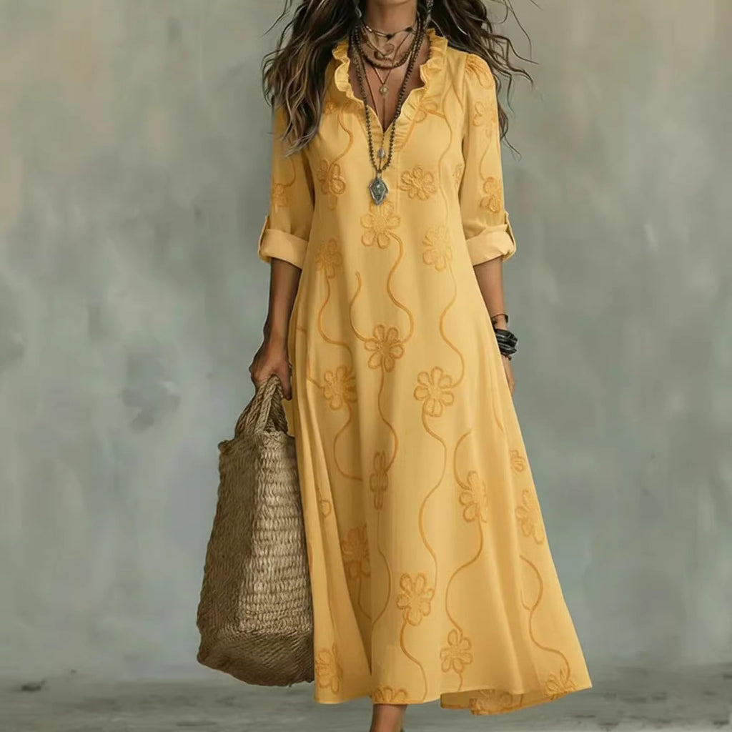 Woman wearing a yellow embroidered dress holding a woven bag against a neutral background
