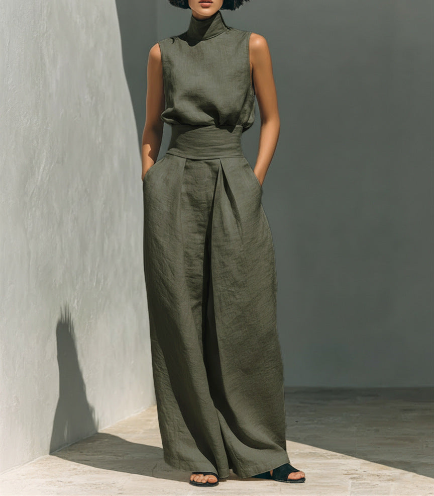Person wearing a green outfit standing against a gray wall.