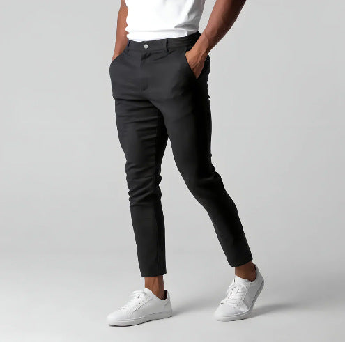 Person wearing black pants and white sneakers on a gray background