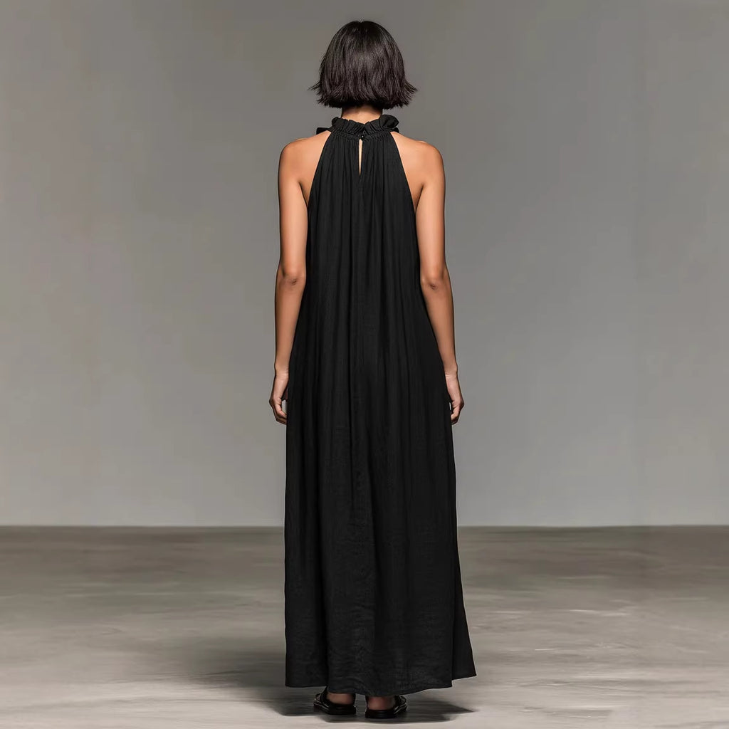 Woman wearing a black halter neck dress against a plain background