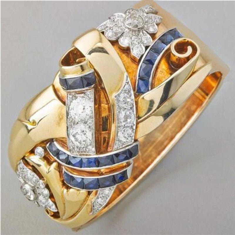 Gold ring with diamonds and blue sapphires on a gray background