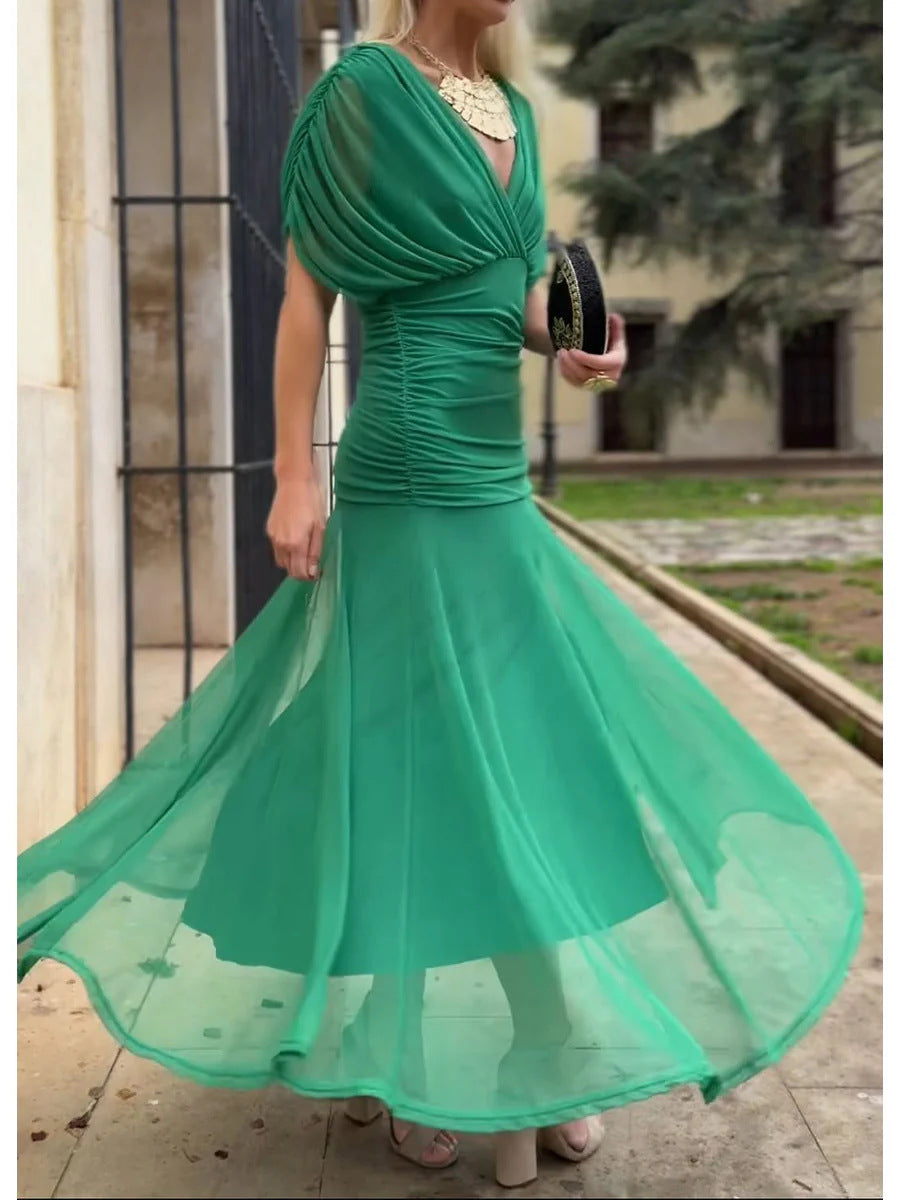 Woman wearing a green dress with a flowing skirt in an outdoor setting.