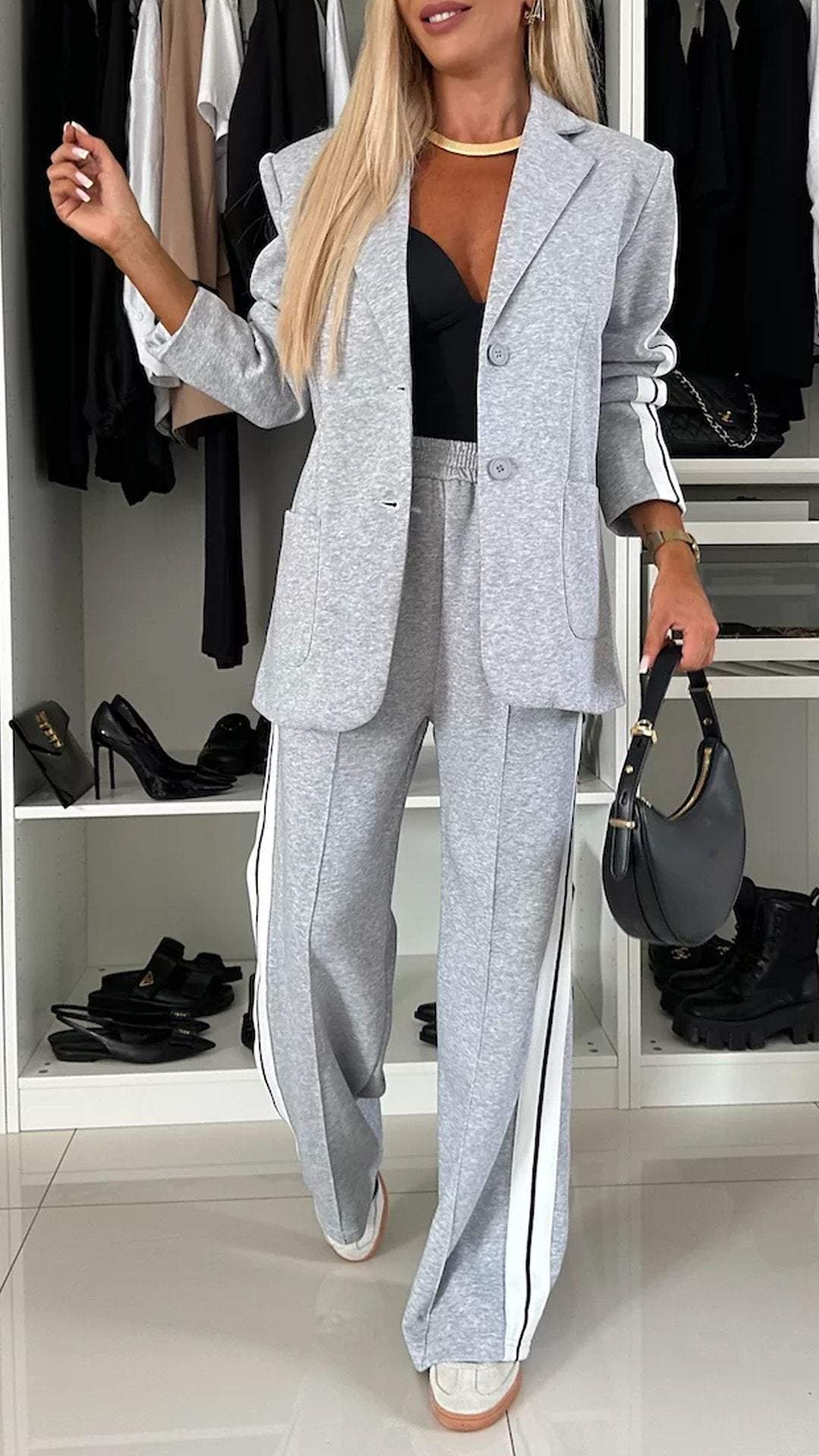 Woman in a gray suit standing in a room with shelves and shoes.