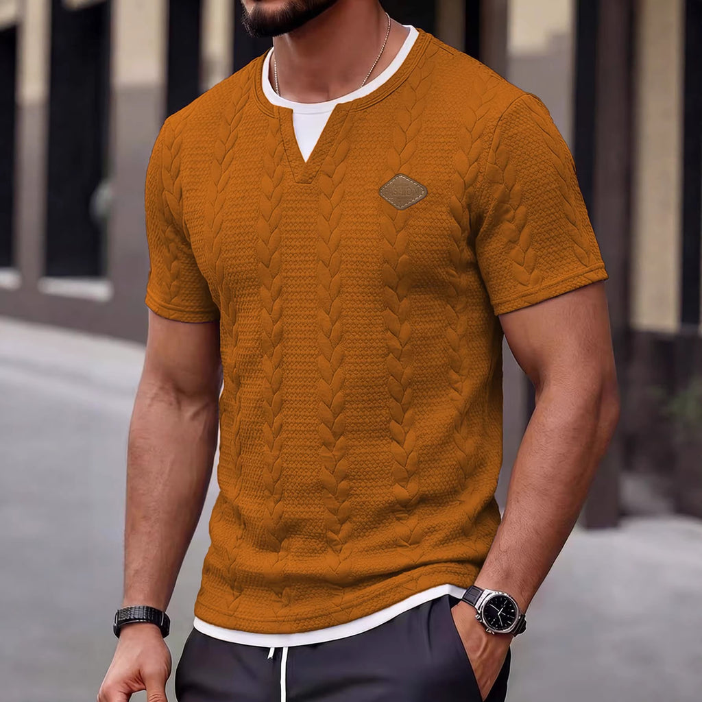 Man wearing a mustard yellow cable knit sweater with a blurred background