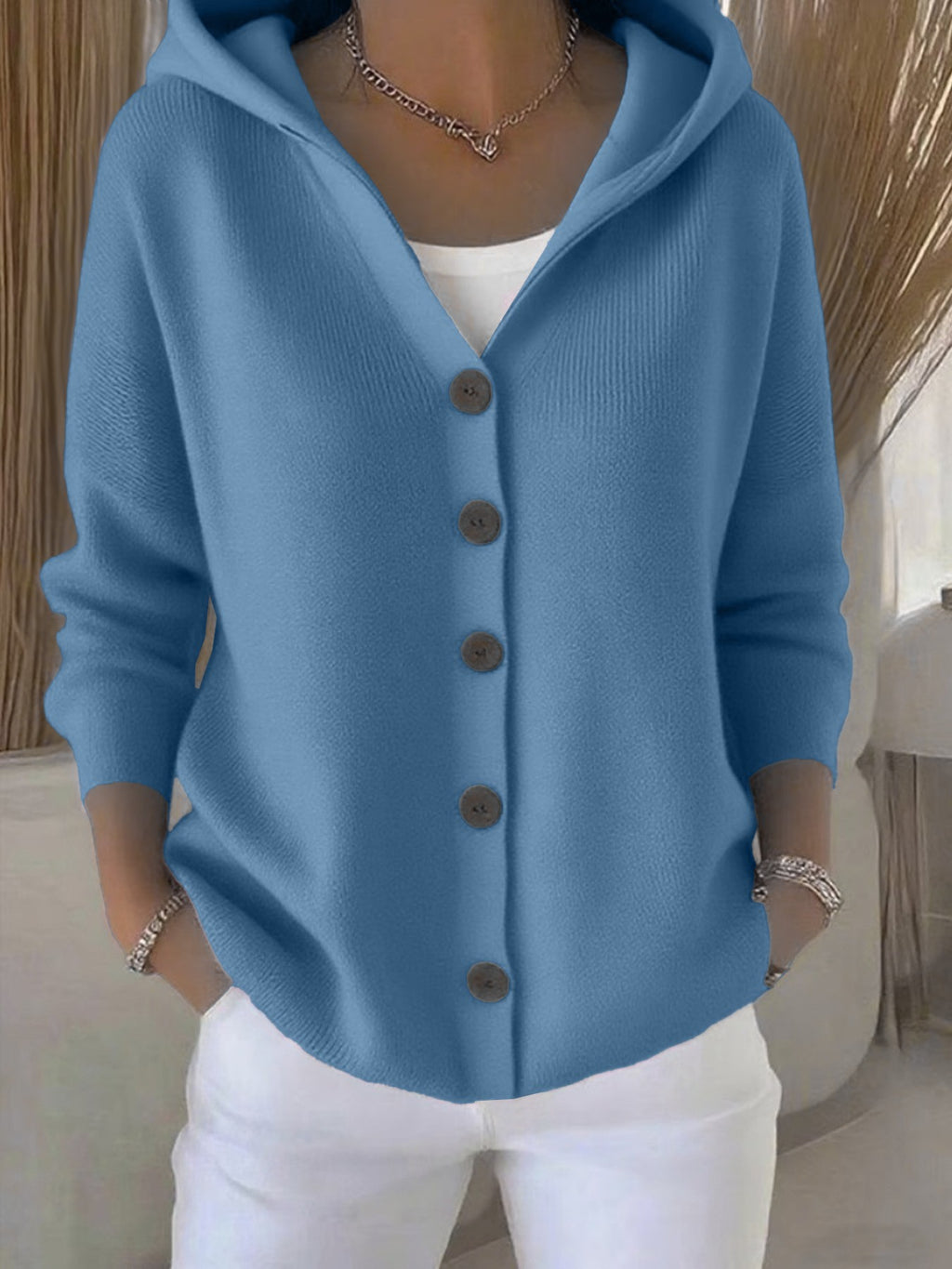 Person wearing a blue cardigan with brown buttons in an indoor setting