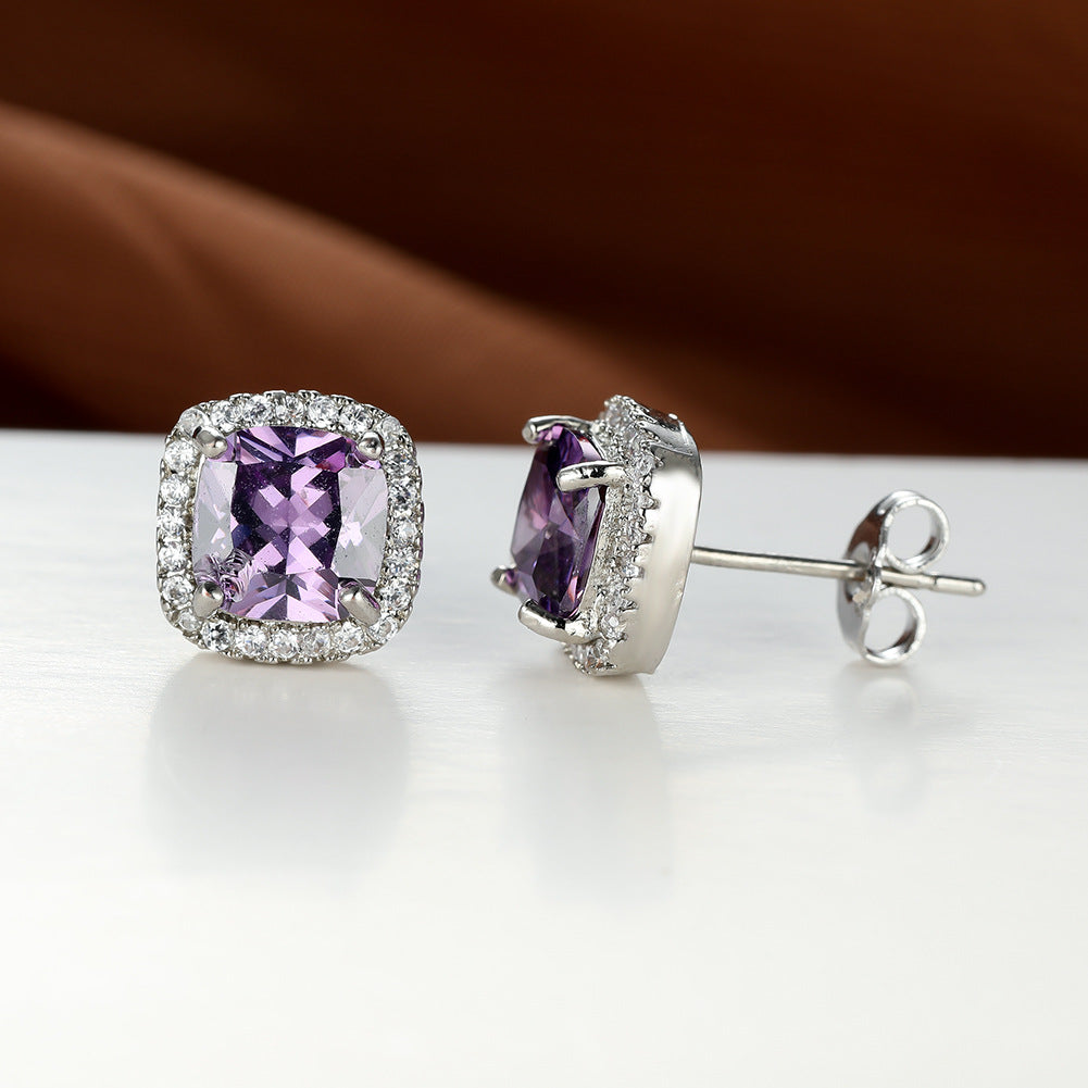 Pair of silver earrings with purple gemstones on a white surface.