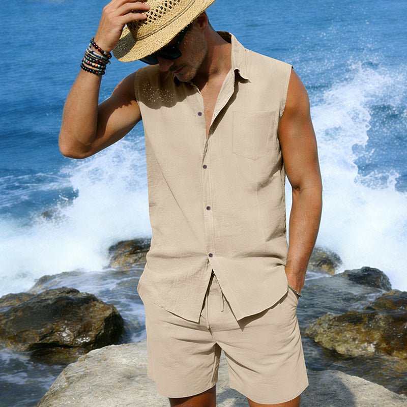 Man in beige sleeveless shirt and shorts standing on rocks with ocean waves in the background