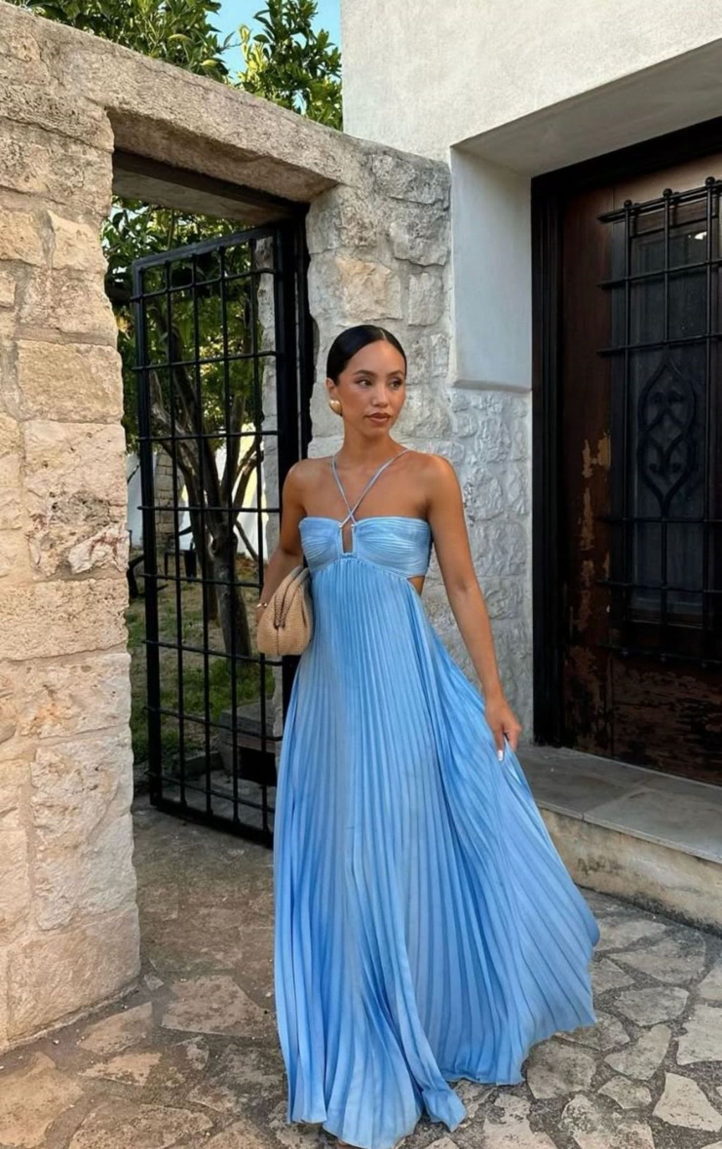 Woman in a blue dress standing in front of a stone building.