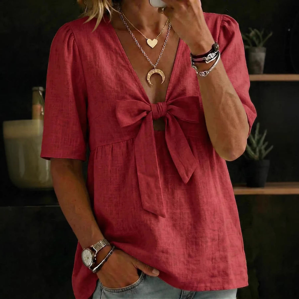 Person wearing a red blouse with a bow detail, standing indoors.