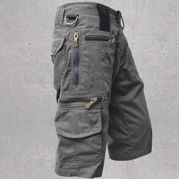 Gray cargo shorts with multiple pockets and zippers on a gray background