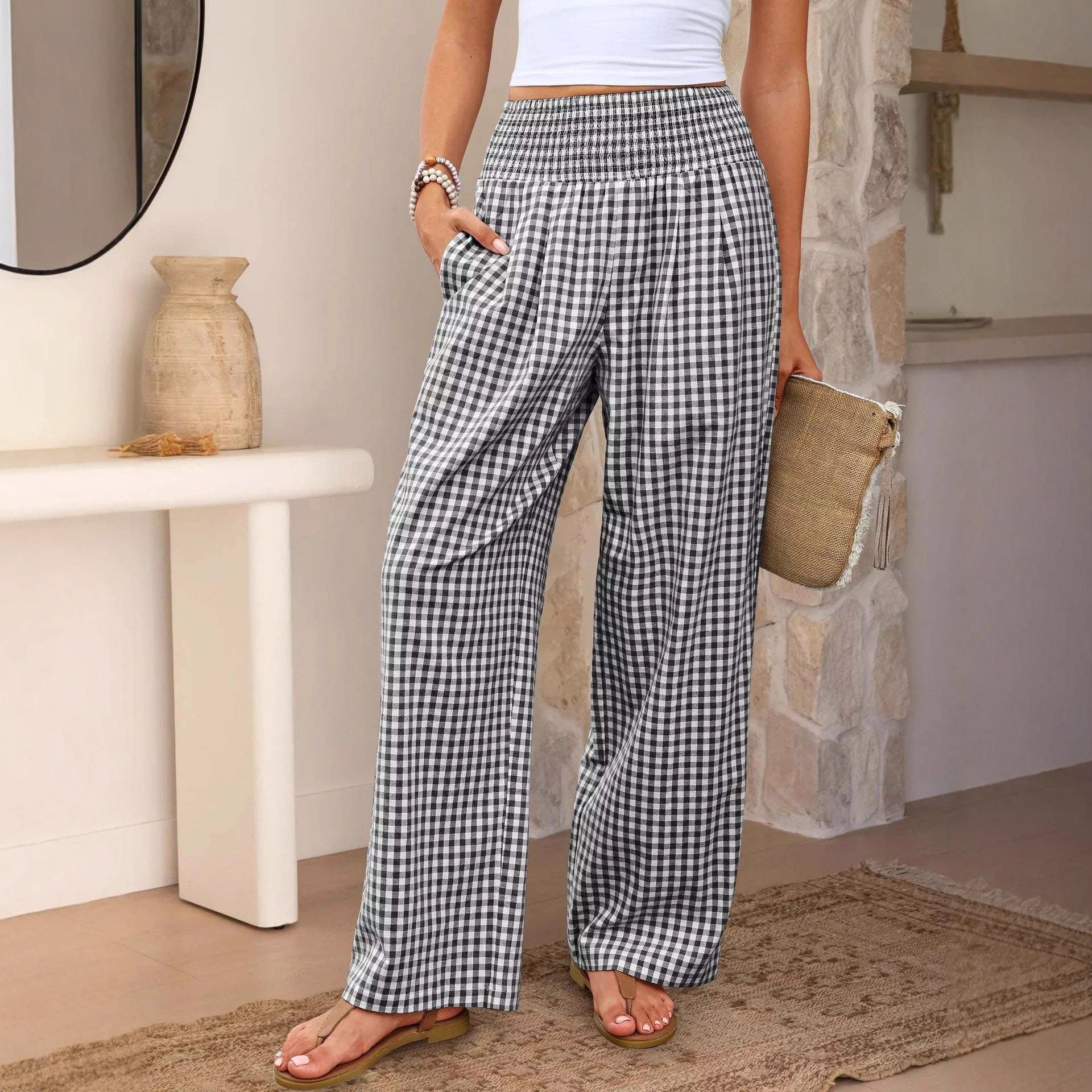 Person wearing checkered pants standing in a room with a stone wall and white table.