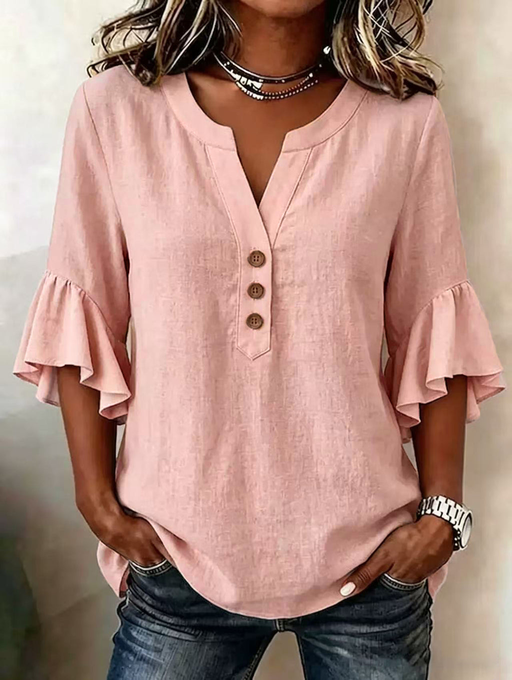 Pink blouse with ruffled sleeves worn by a person on a neutral background