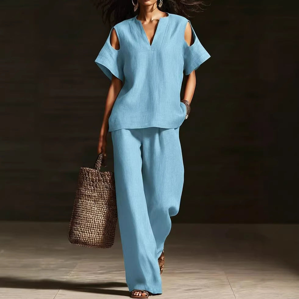 Woman in a light blue outfit holding a woven bag against a dark background