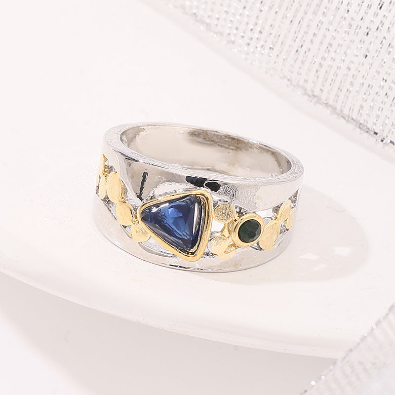 Silver ring with gold accents and a blue gemstone on a white background