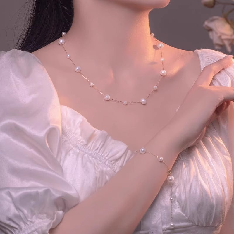 Pearl necklace and bracelet on a person wearing a white dress with a soft focus background