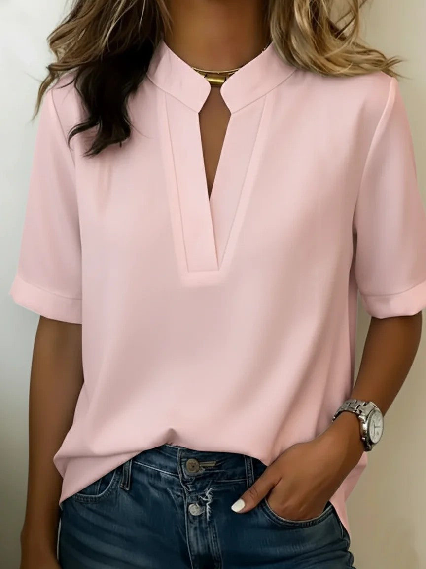 Person wearing a pink short-sleeve blouse with a neutral background
