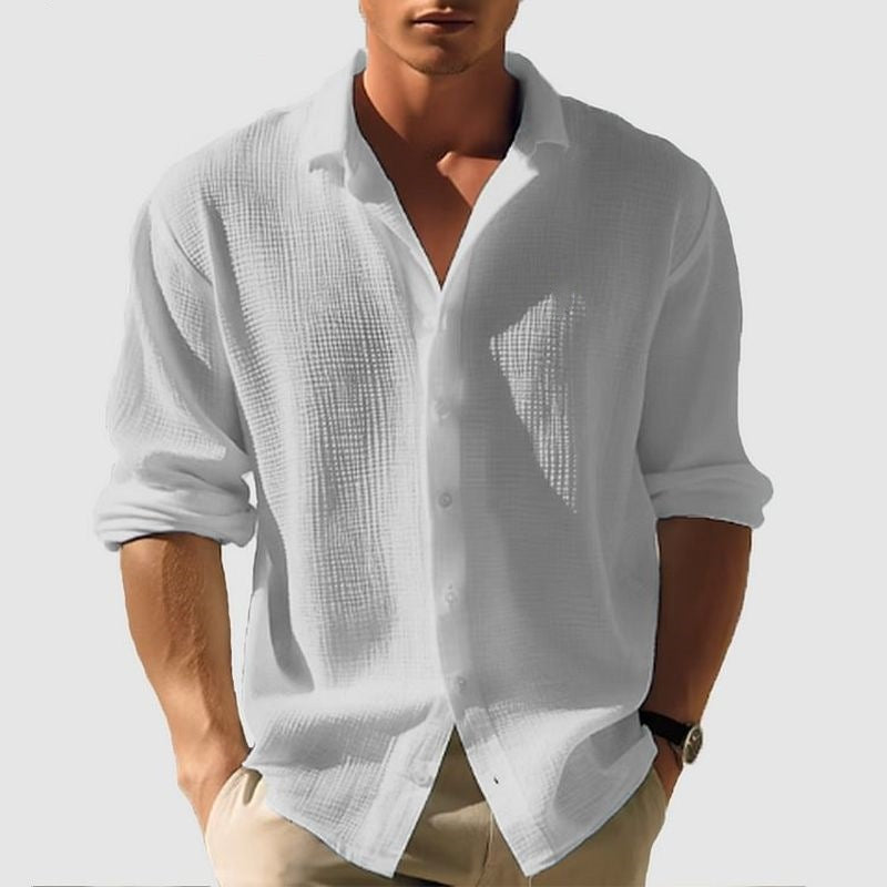 Man wearing a white textured shirt with rolled-up sleeves on a light gray background