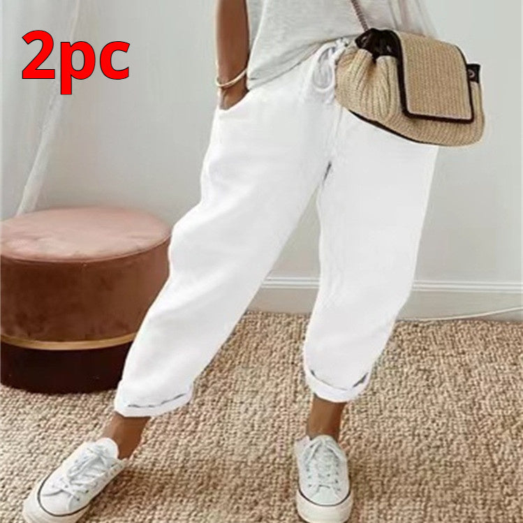 Person wearing white pants and white sneakers with a small bag, standing on a carpeted floor.