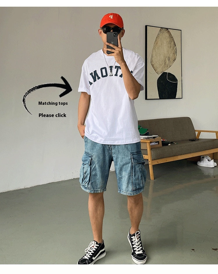 Person wearing a white t-shirt, blue shorts, and a red cap taking a mirror selfie.