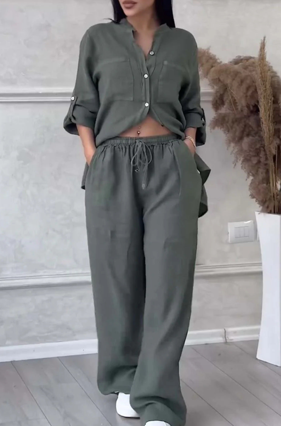 Person wearing a green outfit standing in a room with a neutral background