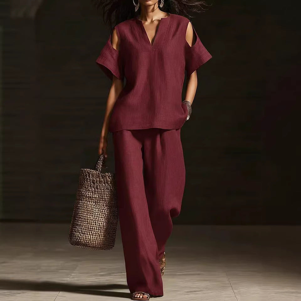 Woman in burgundy outfit holding a woven bag against a dark background