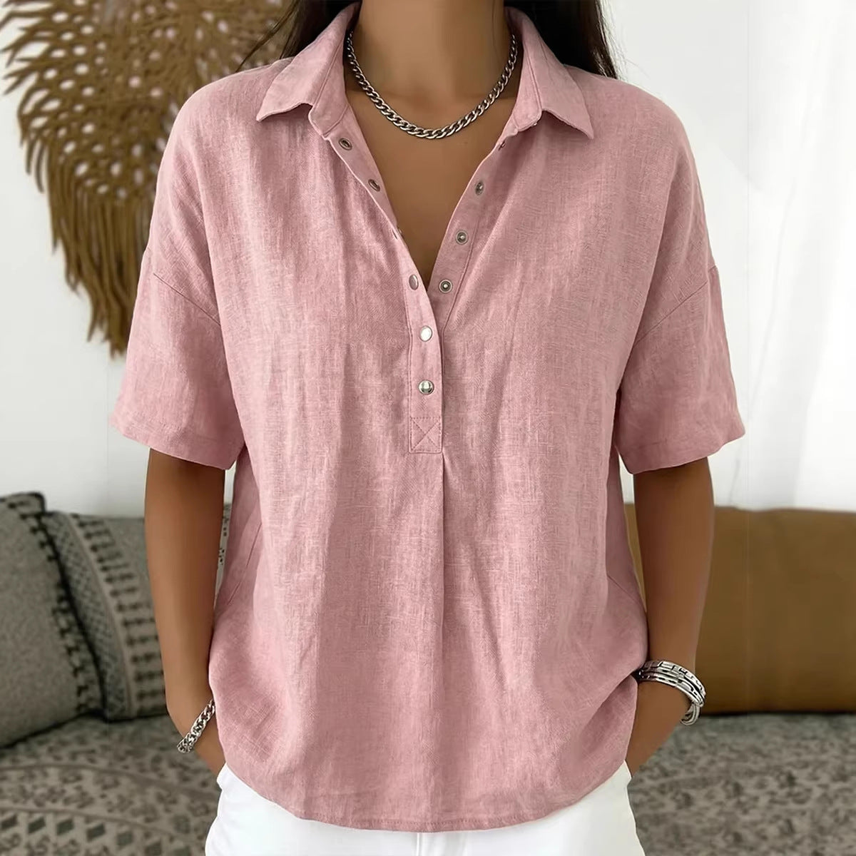 Person wearing a pink short-sleeve shirt with a neutral background