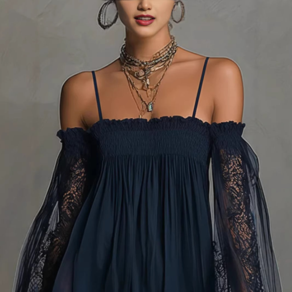 Woman wearing a dark blue dress with sheer sleeves against a gray background