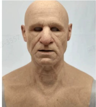 A realistic bald male latex or silicone prosthetic face and neck makeup look-up on a plain light gray background.