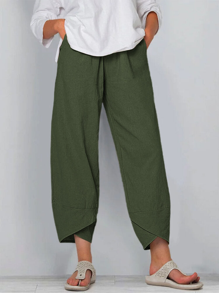 Person wearing green wide-leg pants and a white shirt on a plain background