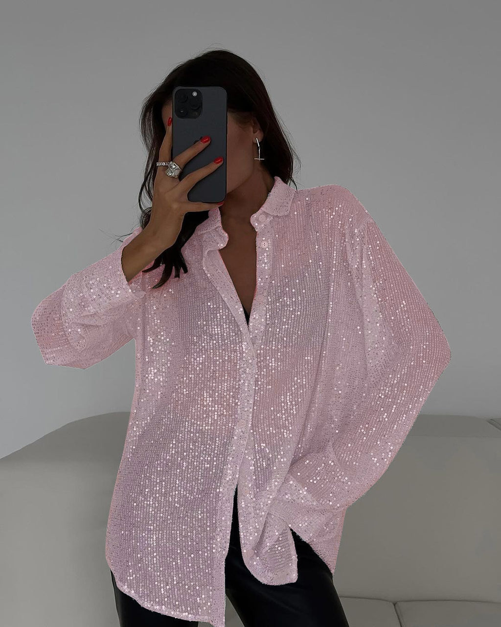 Person wearing a pink sequin shirt taking a mirror selfie.