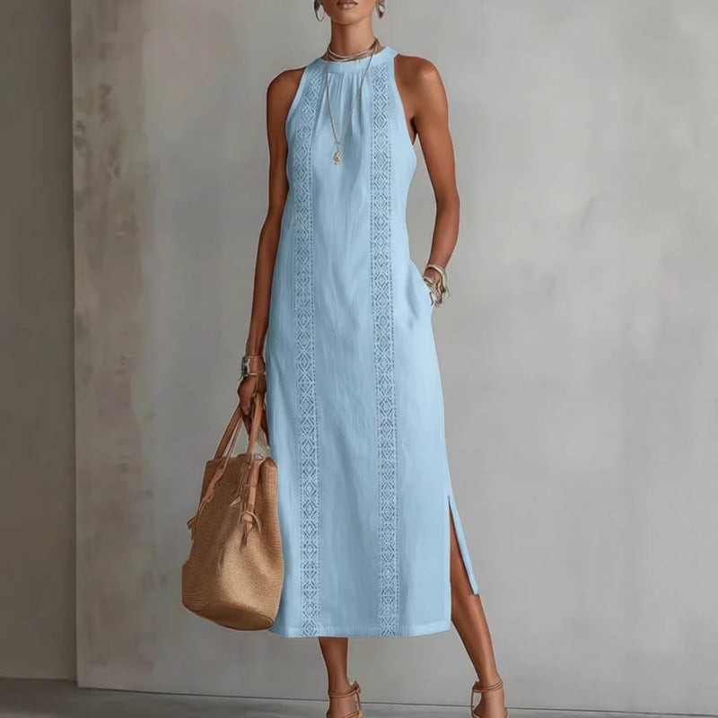 Woman wearing a light blue dress with intricate patterns, holding a beige handbag against a neutral background.