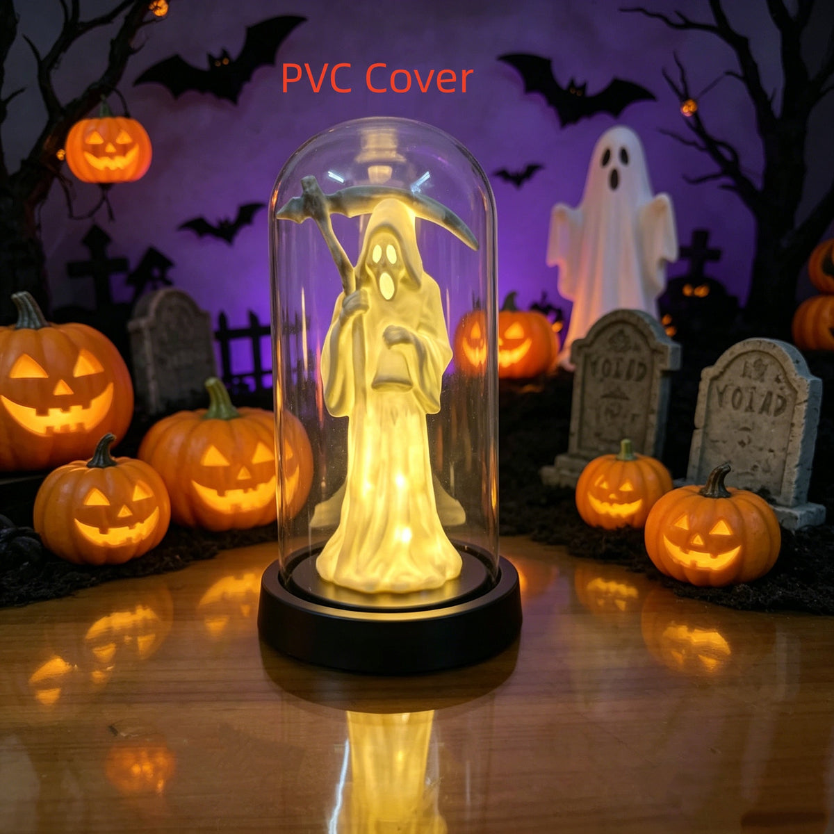 A glowing Halloween decoration featuring a hooded ghost figure inside a clear glass dome on a black base, surrounded by lit pumpkins, tombstones, bats, and a ghost in a spooky purple scene. The text 'Glass Cover' appears at the top.