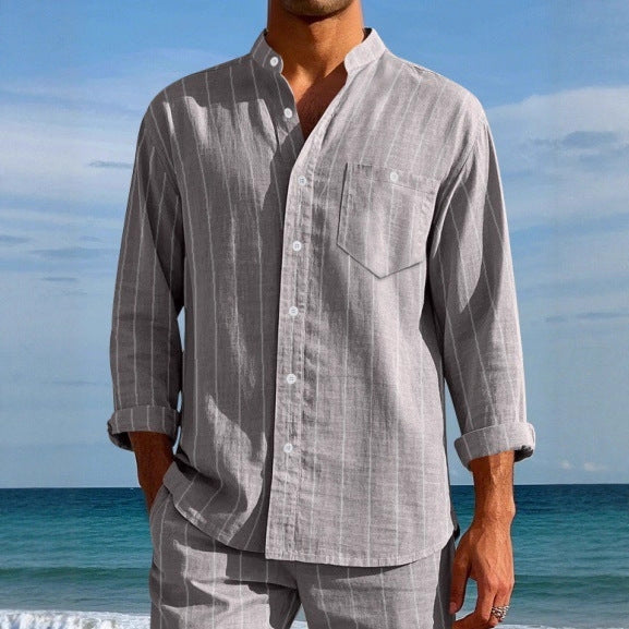 Person wearing a gray striped shirt and pants with a blue sky and ocean background