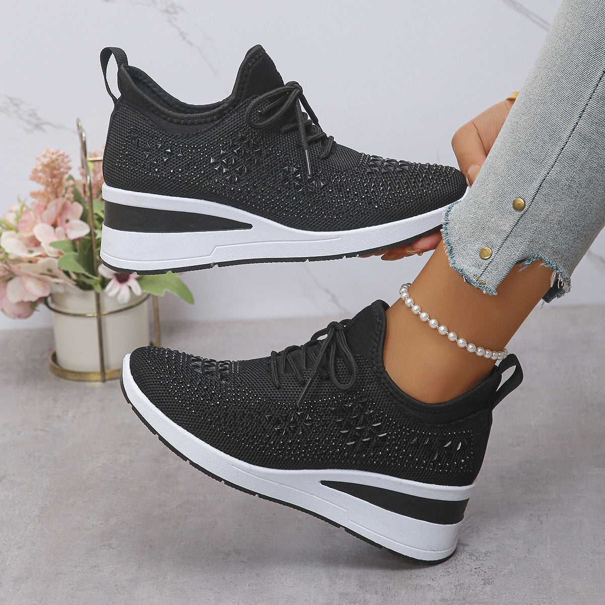 Black and white sneakers worn by a person with a light gray background