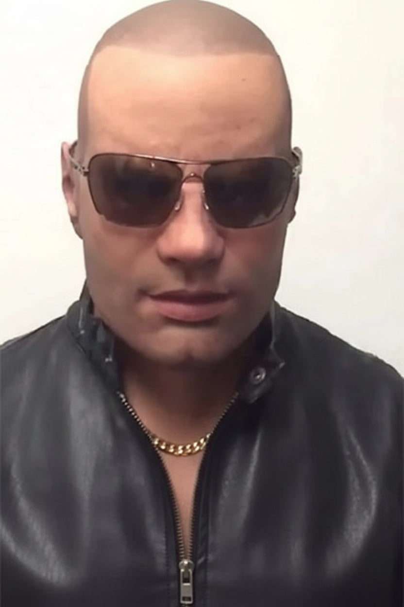 A close-up of a bald man wearing dark aviator-style sunglasses and a black leather jacket, against a plain light background with a Chinese text watermark across the middle.