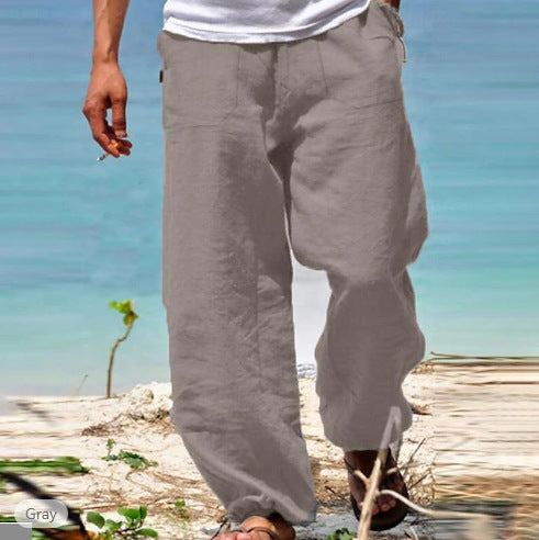 Person wearing gray pants standing on a beach with clear blue water in the background