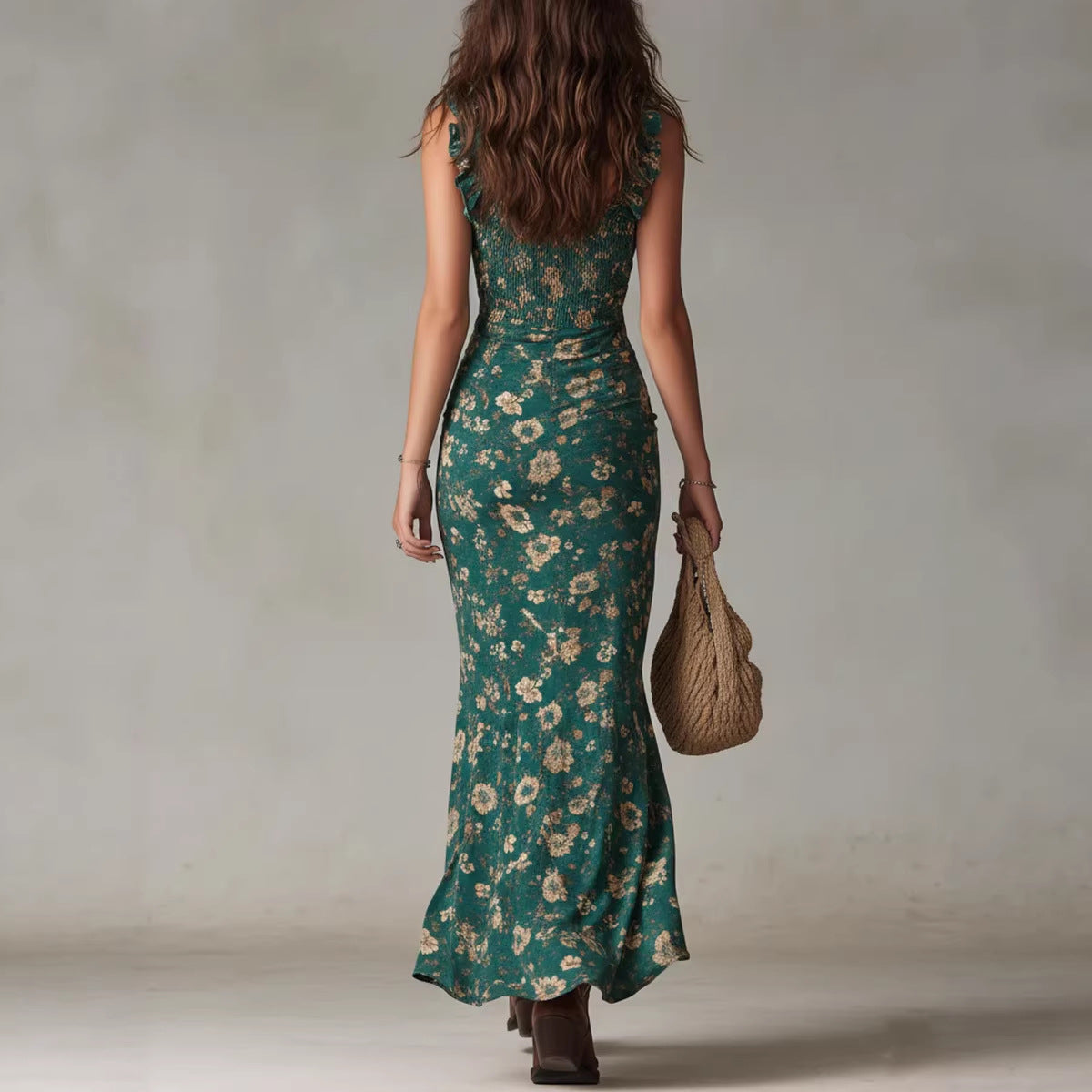 Woman wearing a green floral dress holding a woven bag against a neutral background