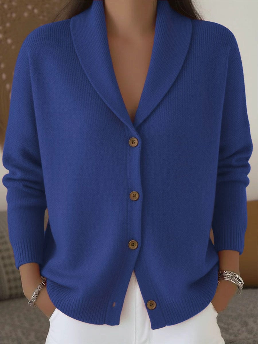 Blue cardigan with brown buttons worn by a person, against a neutral background