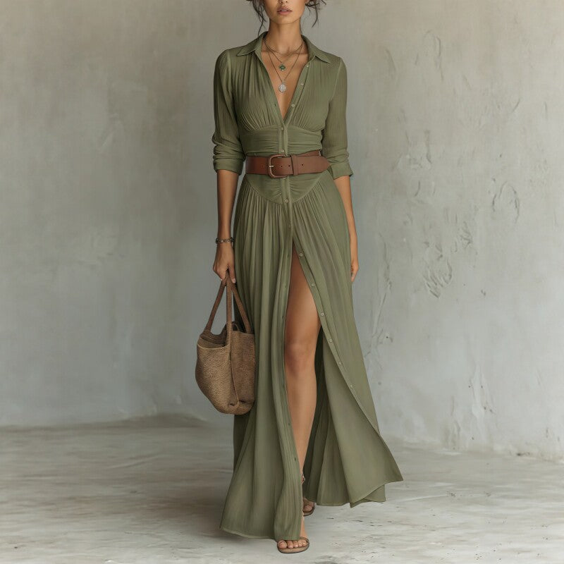 Woman wearing a long green dress with a slit, holding a brown bag against a plain background
