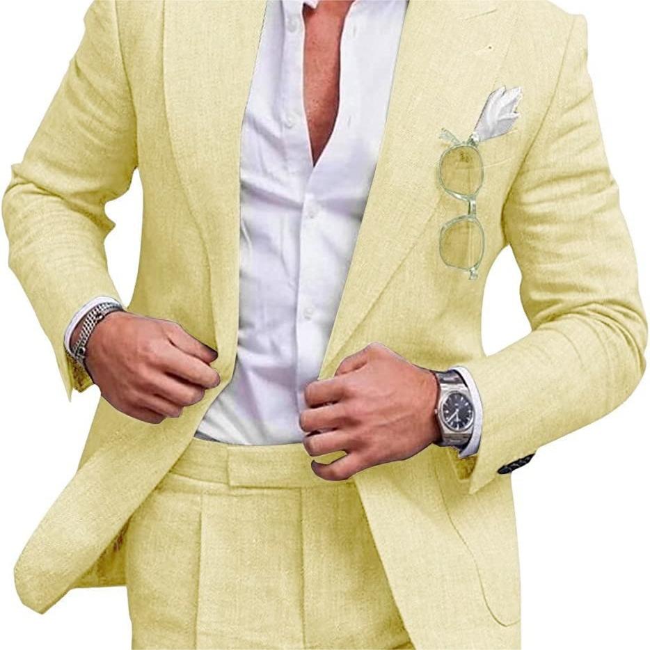 Man wearing a light yellow suit with a white shirt, glasses in pocket, and watch on wrist.