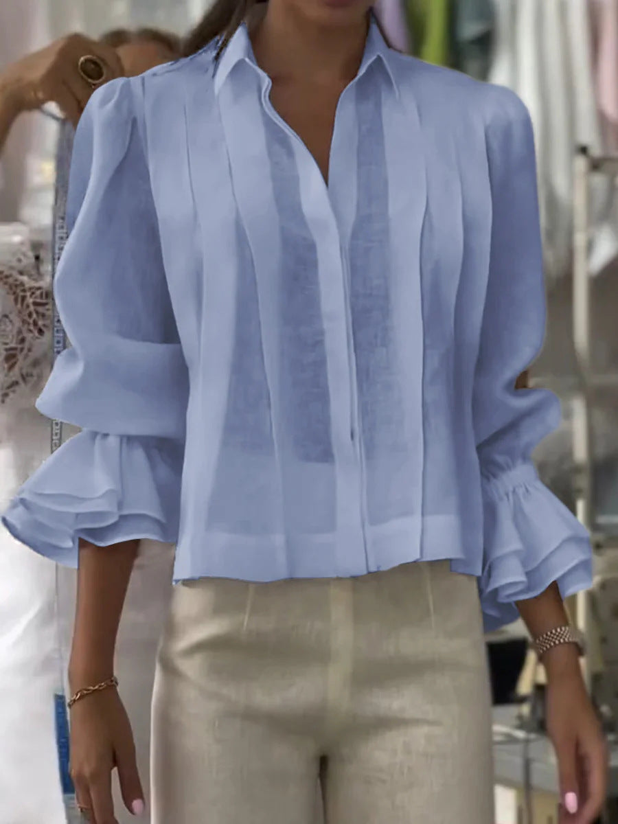 Light blue blouse with ruffled sleeves worn by a person, blurred background