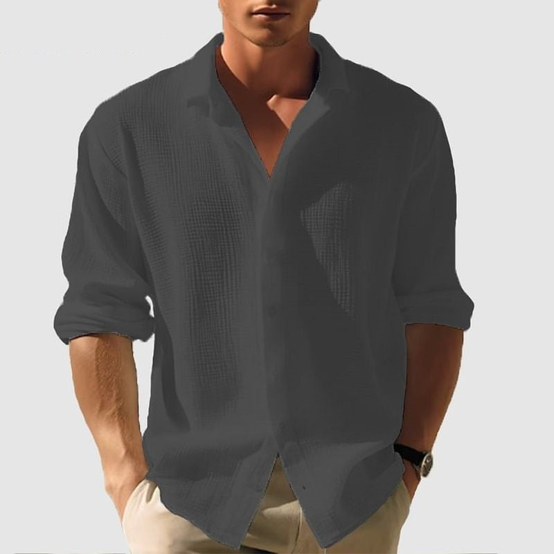 Man wearing a dark gray textured shirt with rolled-up sleeves on a light gray background