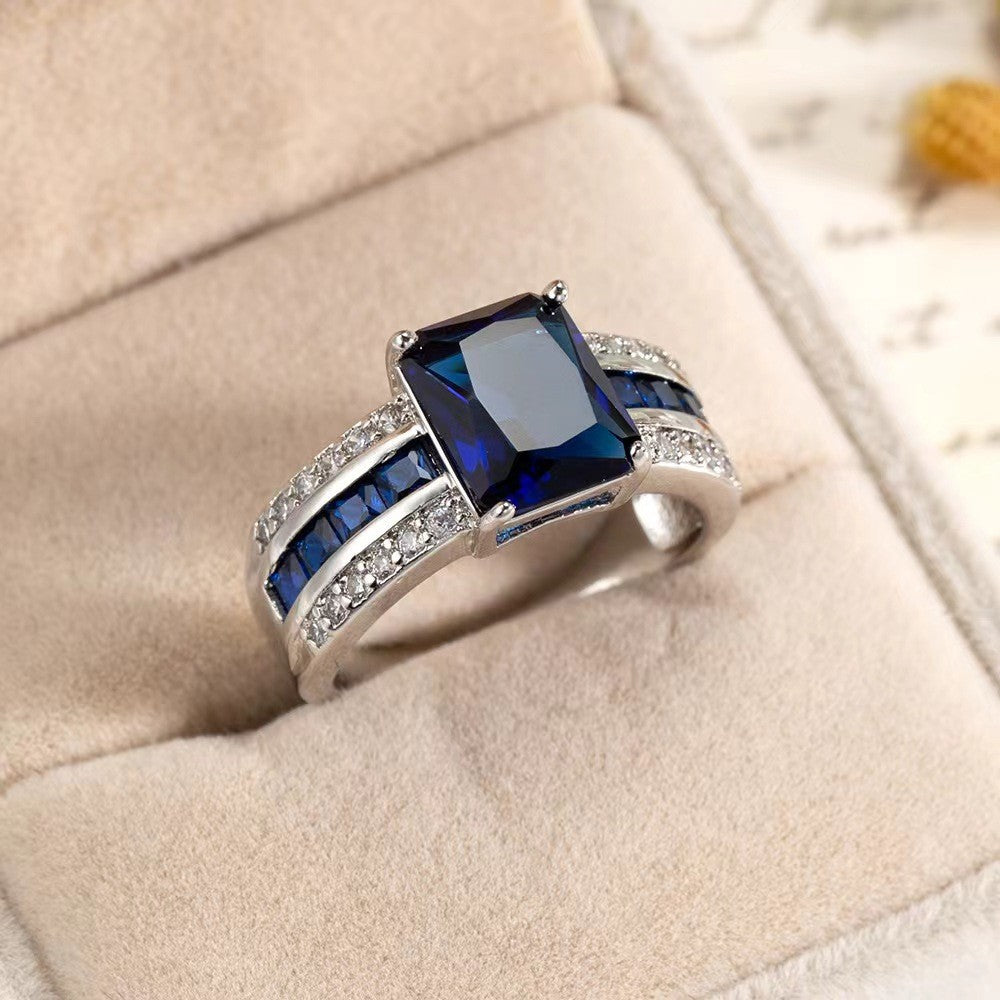 Silver ring with a blue gemstone on a beige cushion