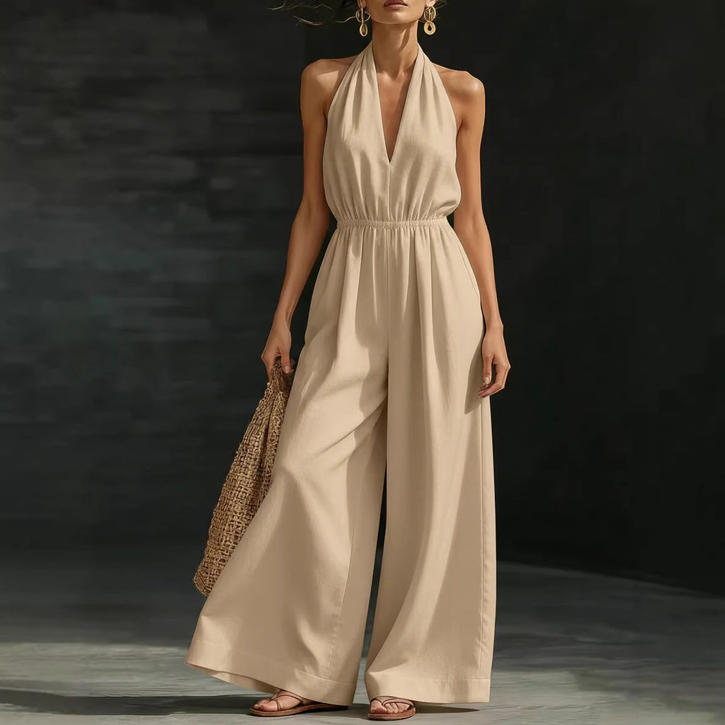 Woman wearing a beige jumpsuit holding a woven bag against a dark background