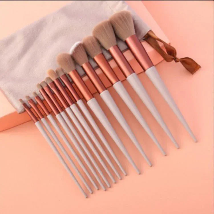 Set of rose gold and white makeup brushes with soft bristles and pouch on peach background