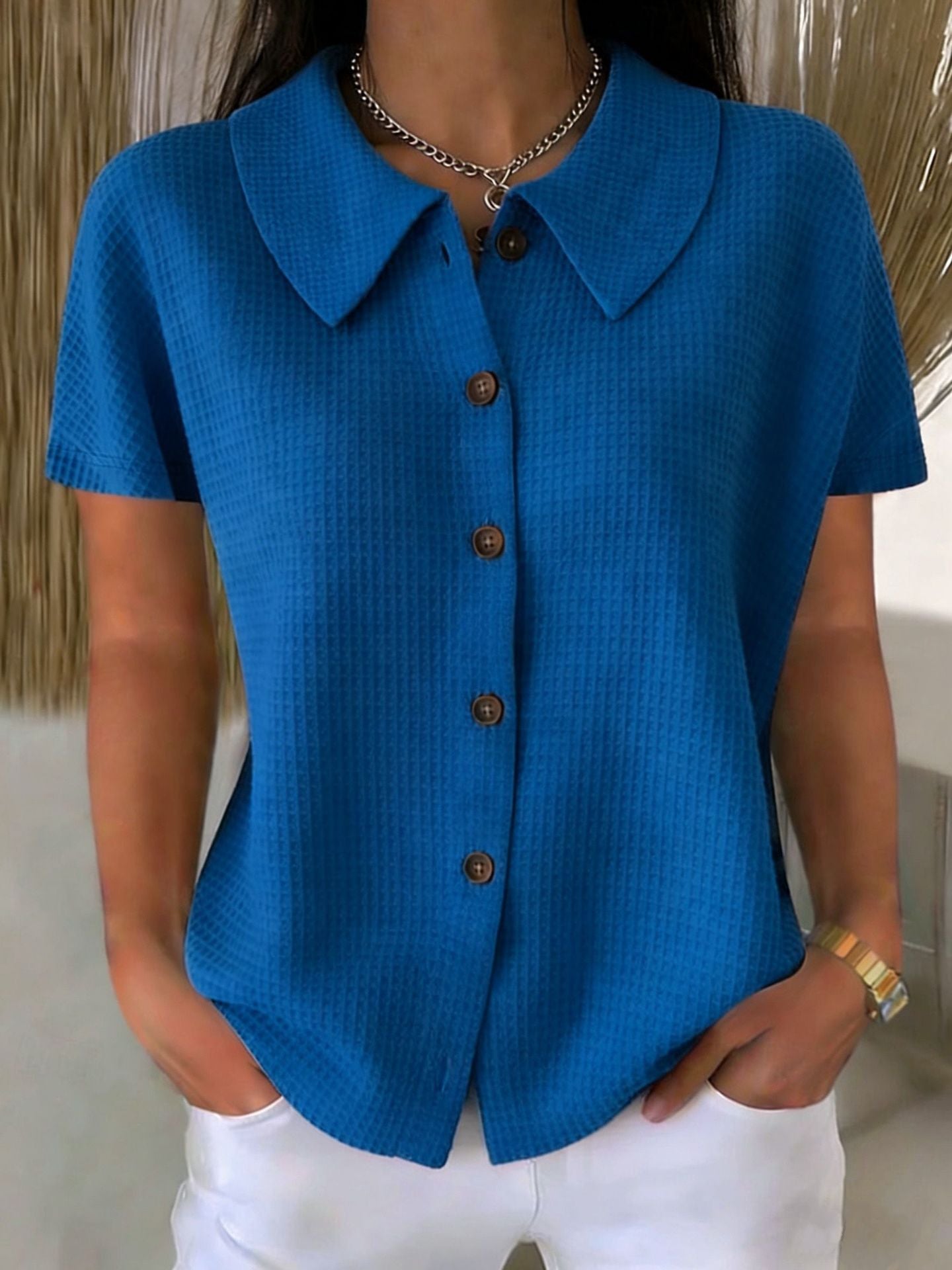 Blue short-sleeve button-up shirt worn by a person with a neutral background