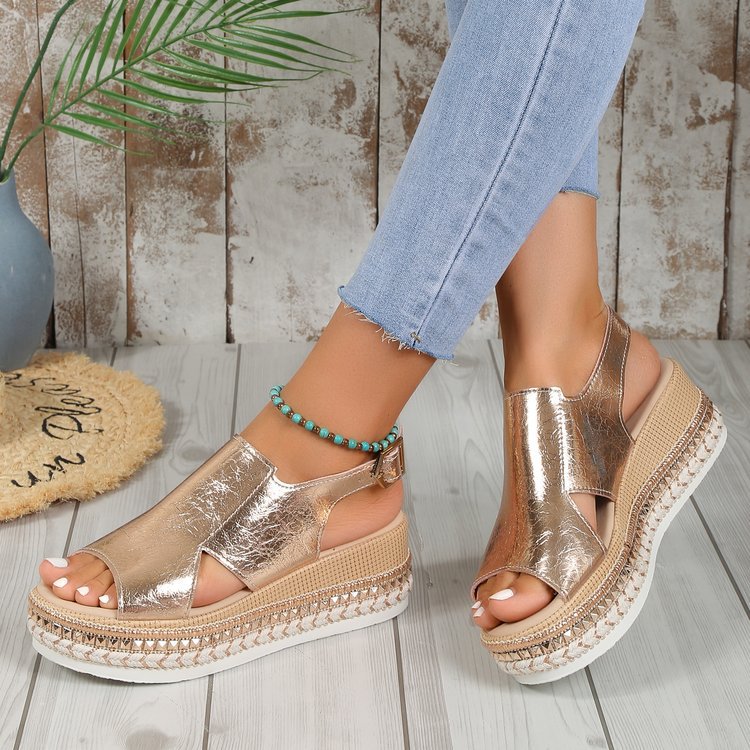 Gold platform sandals worn with light blue jeans on a wooden floor.