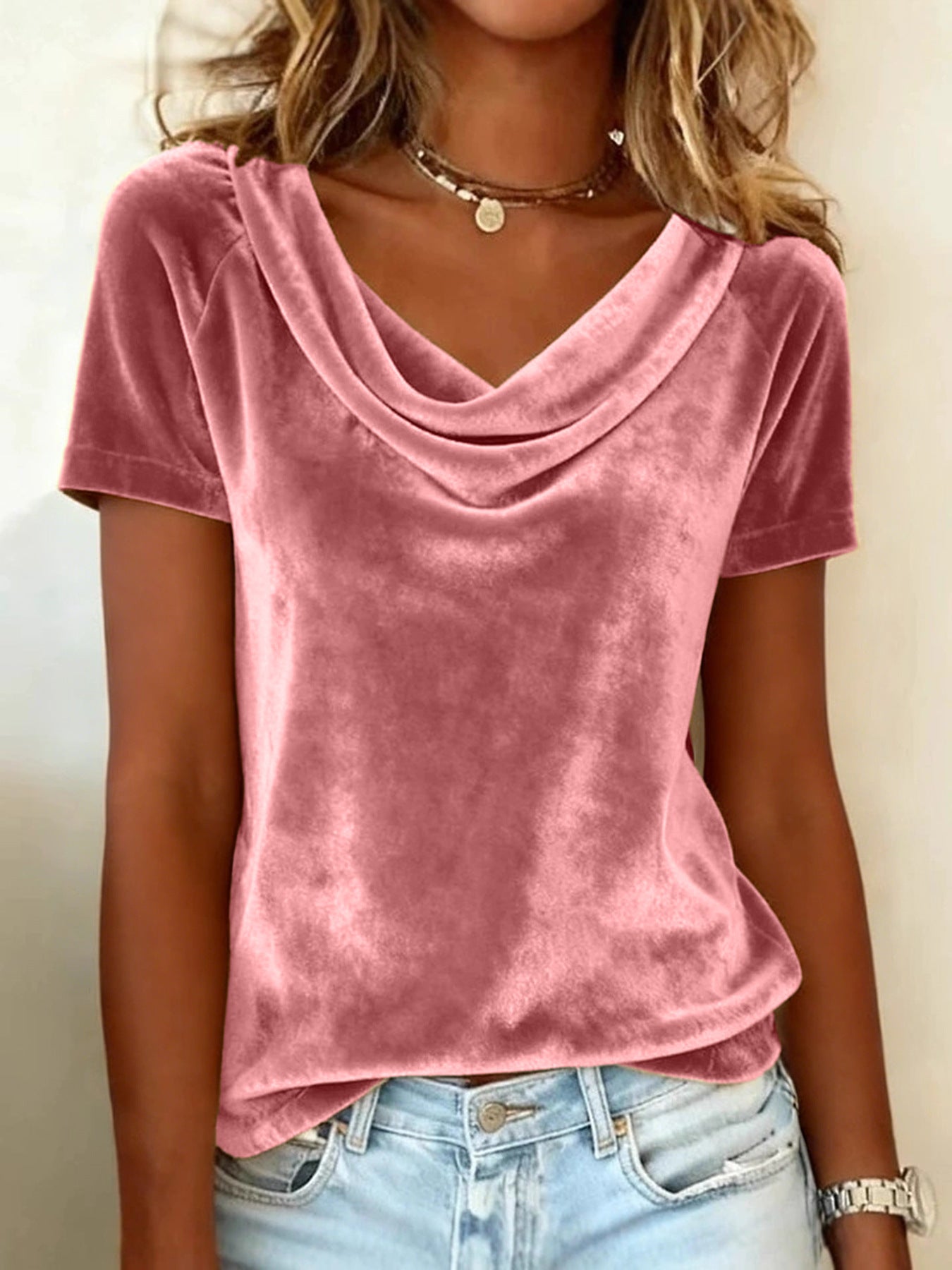 Person wearing a pink velvet top and light blue jeans against a neutral background