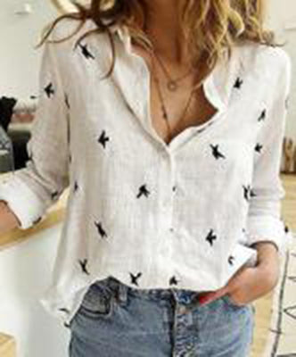 White blouse with black butterfly patterns worn by a person indoors.